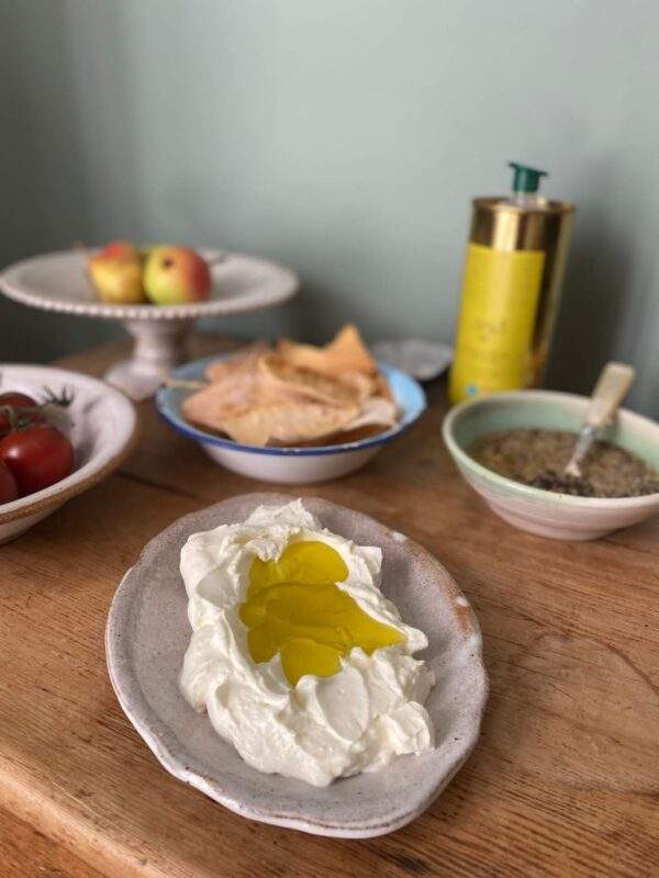 labneh on a plate with evoo on a table with breakfast items
