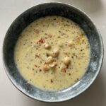 a bowl of yoghurt soup with orzo and chickpeas and saffron on the top