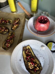 pomegranate tapenade on top of roasted aubergine garnished with pomegranate seeds and pine nuts
