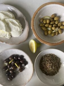 a plate of labneh, black olives, green olives and za'atar