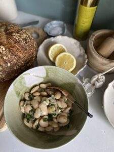 butter beans in a bowl with garlic, lemon, EVOO and some bread