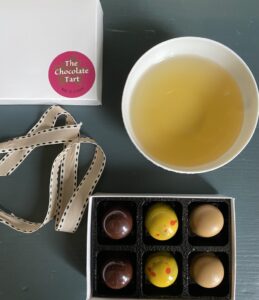 a cup of olive leaf infusion beside a box of chocolates