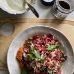 grated beetroot and celeriac, with sliced kohlrabi, blood orange segments, with a few parsley leaves, capers, and a yoghurt sumac dressing on a plate