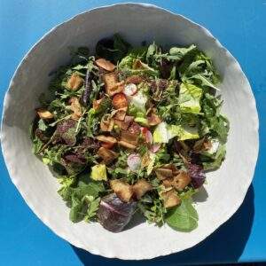 a bowl with fattoush salad on a blue table