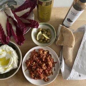 muhammara in a bowl with olives, labneh, radicchio and some bread