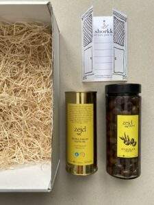 a tin of extra virgin olive oil and a jar of souri black olives with a box and a gift card