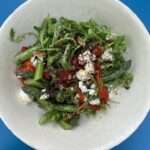 a salad bowl of asparagus with red peppers, feta and rocket and pomegranate molasses dressing