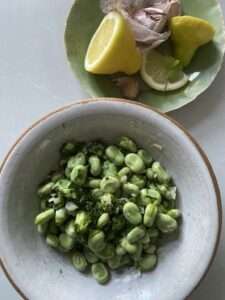 a plate of broad beans with garlic and coriander and some lemon