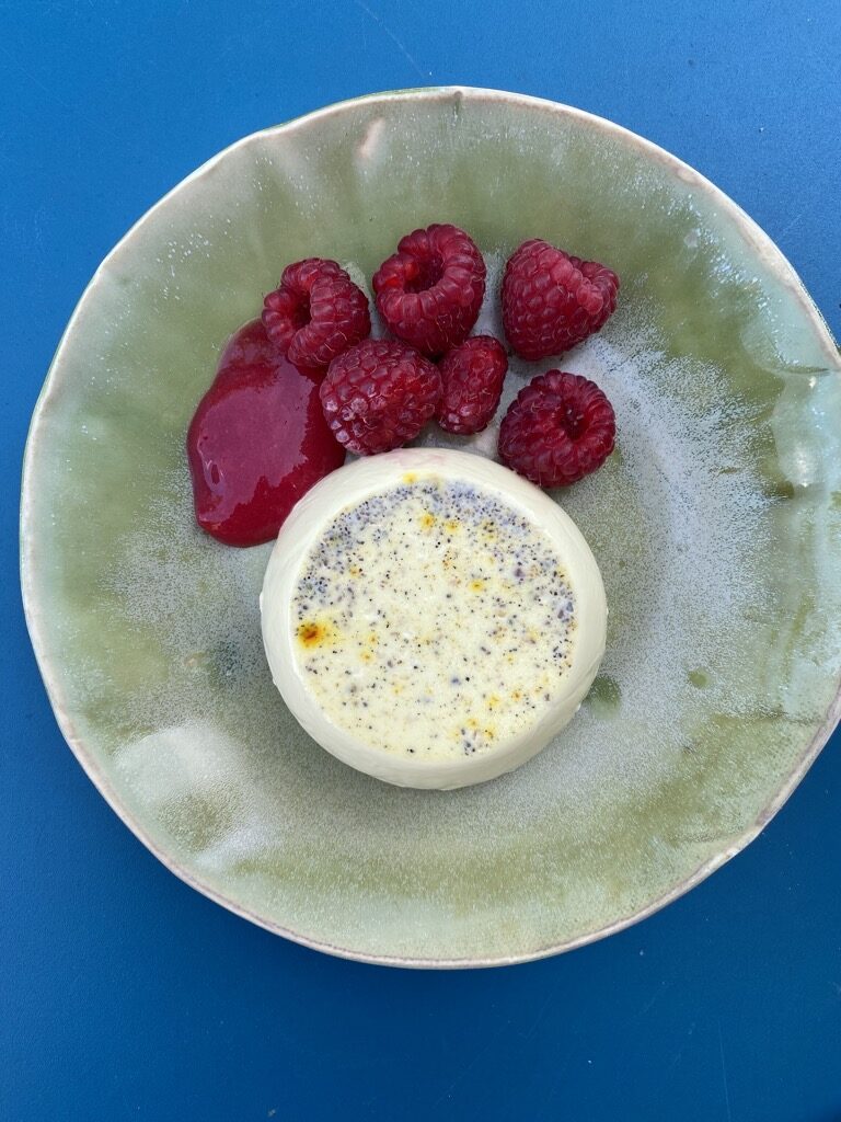 panna cotta with a red current couli and some raspberries