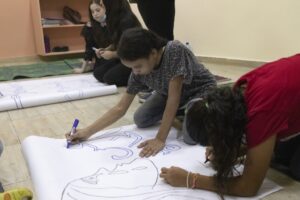 two teenage girls designing a piece of artwork in the classroom of Shatilla camp