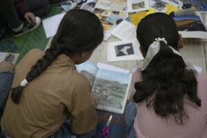 Two girls in a classroom looking a pictures