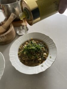pouring evoo over a plate of lentils and pasta "rishta"