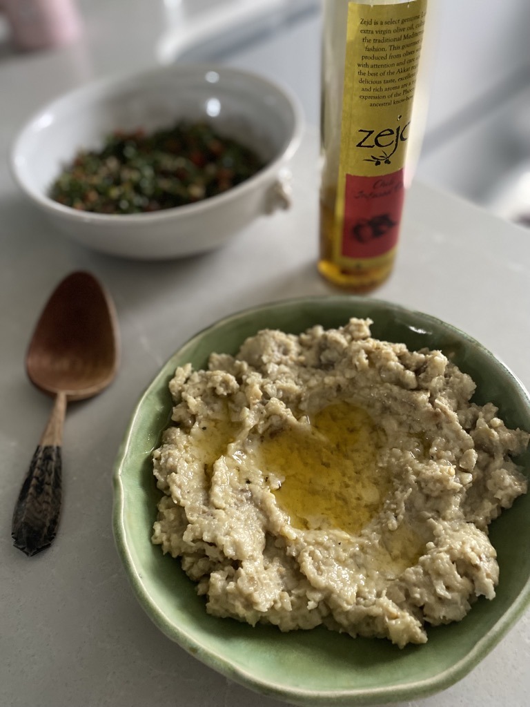 a plate of baba ghanouj with some chilli infused oil, a bottle of Zejd chilli infused oil and a bowl of tabouleh