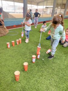 children placing a bottle in a cup as part of a team game organised by Najdeh